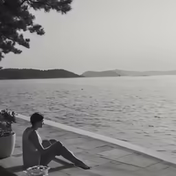 a person sitting on a ledge next to the ocean