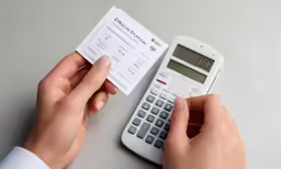 someone with their phone is checking a receipt on their calculator
