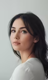 a woman with dark hair and blue eyes wearing white