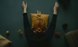 a person with their arms up next to a pillow