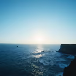 the sun shining through clouds over a rocky cliff