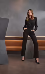 a woman posing in black pantsuits with high heels