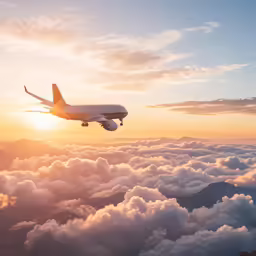 an airplane flying high above clouds in the sunset
