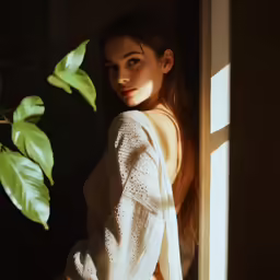 a beautiful woman in white posing by a window