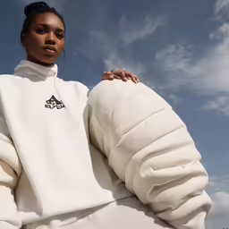 a woman is posing wearing a white turtleneck sweater