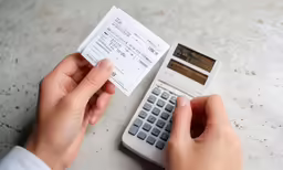 a person sitting in front of a calculator with a receipt