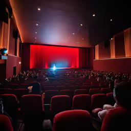 people in a large auditorium watching an on screen movie