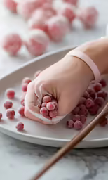 pink candies being spooned into a white bowl