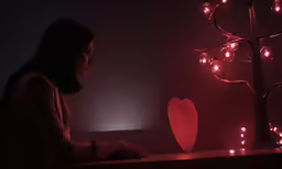 a woman sitting in front of a lit heart