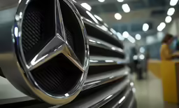 mercedess logo on the front grill of a car in an automobile showroom