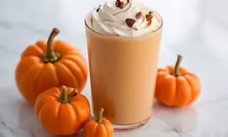 two cups of coffee with whipped cream and mini pumpkins