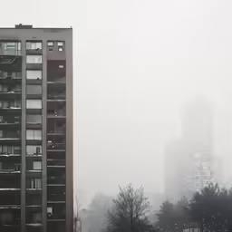 a large building in a foggy area with buildings in the background