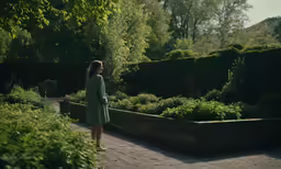 a woman stands outside while looking at the garden