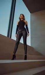 the woman in black clothes is posing on a staircase