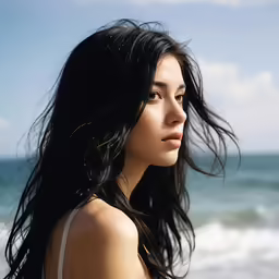 the head and shoulders of an asian woman standing on a beach