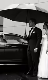 a man and woman in wedding outfits are standing under an umbrella