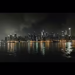 city lights shine as smoke and fog fill the skyline over water