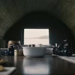 a bowl, camera and lens are on a counter