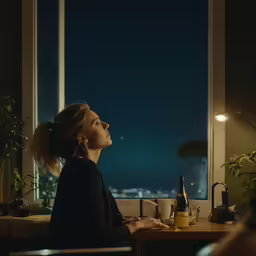 woman sitting by the window with a bottle and wine