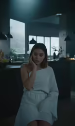 a woman sitting in a chair with her hands behind her face