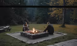two people sitting around a fire pit, using remote controls