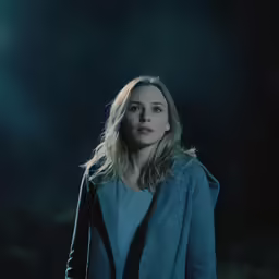 a woman in a blue jacket is standing alone