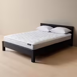 the top of a bed is shown with white pillows