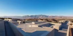 an aerial shot shows the roof of a building and mountains in the background