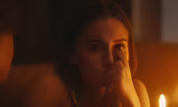 woman is staring in a dark room with candles