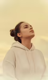 a female in a white hoodie looks upward