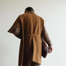 man holding brown purse in the back