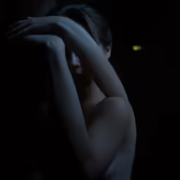 a nude woman posing with her hands on her shoulder