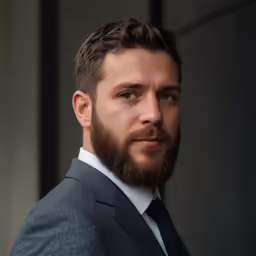 a young man with a beard wearing a suit and a white shirt