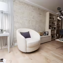 a white chair and bookcase in the corner of a living room