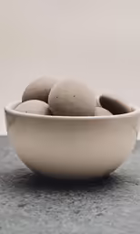 a white bowl of balls on top of a counter