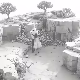 a person stands alone near several stone structures