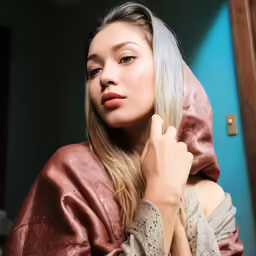 a woman is wearing a satin hooded robe