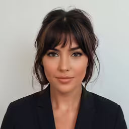 a woman in a black suit with bangs and makeup