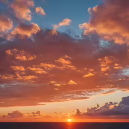 a sunset on a cloudy sky over the ocean