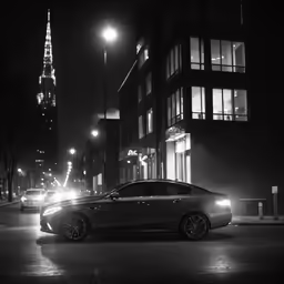 an illuminated black car in the middle of the city at night