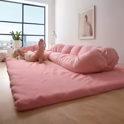 there is a person that is sitting on a large pink sofa