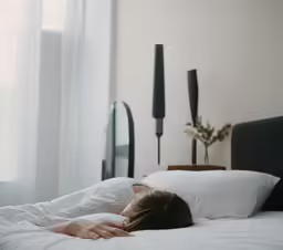 someone laying in bed looking through the window