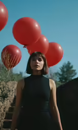 woman in black dress and red balloons flying overhead