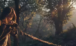 the girl holds up her camera in the woods