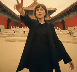 a woman holding her hand up with a building in the background