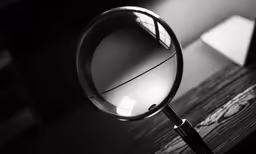 a magnifying glass on a wooden table in the dark