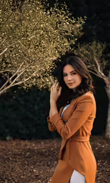 a woman standing by an olive tree while talking on the phone