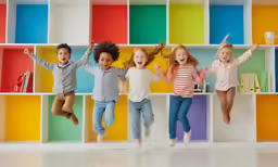 the children are jumping in front of a wall of color blocks