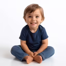 a young child is sitting with his feet crossed and smiling