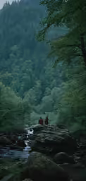 two people in red sitting on rocks by the water